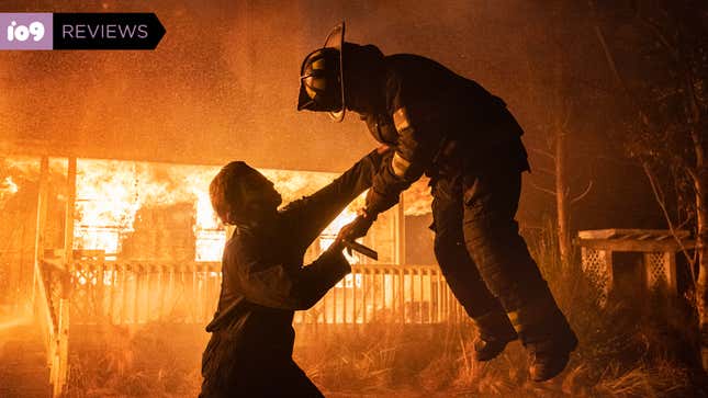 Michael Myers lifts a firefighter up in front of a burning house in a scene from Halloween Kills.