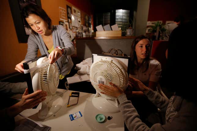 A group of women work on a home air filtration system using fans and filters.