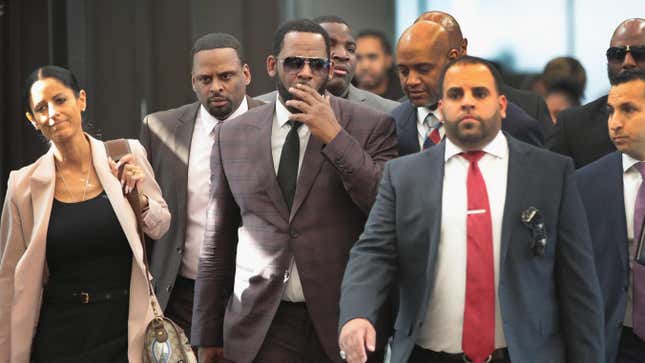 R. Kelly covers his mouth as he speaks to members of his entourage as he arrives at the Leighton Criminal Courts Building for a hearing on June 26, 2019 in Chicago, Ill.