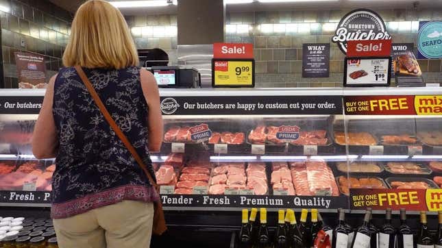 Back of shopper standing in front of supermarket butcher counter