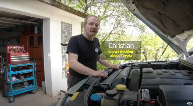 A bespectacled German man who knows nothing about Toyota stands in front of an open Land Rover engine bay
