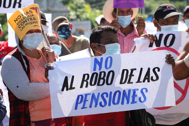 A man holds a sign with a message that reads in Spanish; “Don’t steal  our pensions,” during a protest against the country adopting Bitcoin as  legal tender, along the Pan-American Highway, in San Vicente, El  Salvador, Tuesday, Sept. 7, 2021.