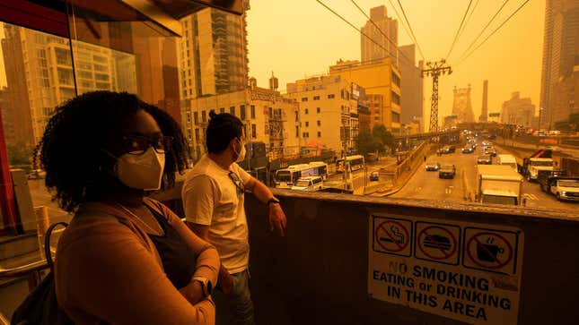  People wear masks as they wait for the tramway to Roosevelt Island as smoke from Canadian wildfires casts a haze over the area on June 7, 2023 in New York City.