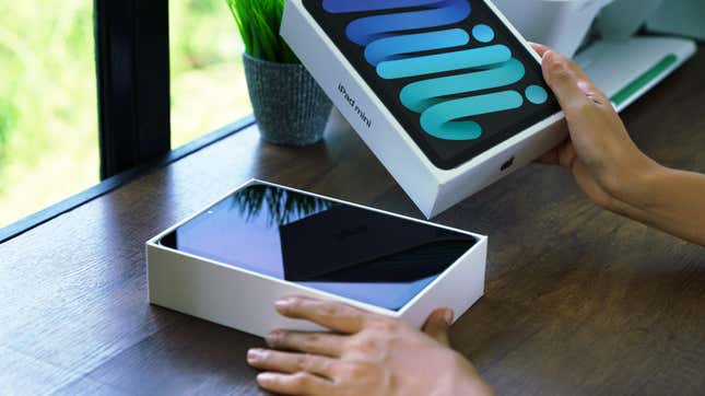 A pair of hands is seen unboxing an iPad mini