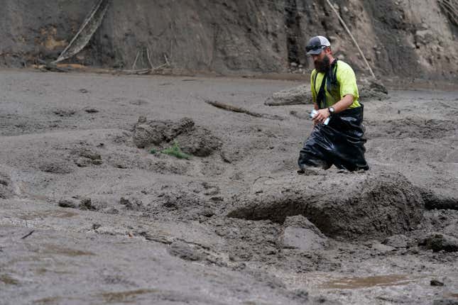 A worker with the Yucaipa Valley Water District threads through knee-deep mud while repairing a reservoir used as a drinking source in the aftermath of a mudslide, on Tuesday, Sept. 13, 2022, in Oak Glen, California. 
