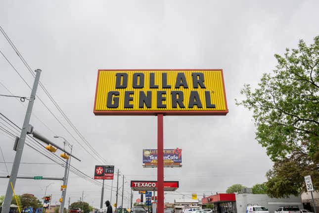 A yellow and black Dollar General convenience store sign attached to a poll set against a gray sky.