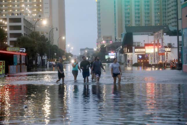 People walk up a flooded Ocean Boulevard in North Myrtle Beach, S.C. on August 30, 2023, after the passage of Hurricane Idalia. 