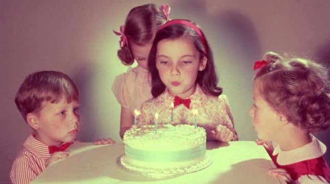A 1950s photo of a girl blowing out the candles on her birthday cake