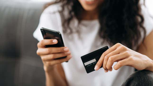A woman holding her phone and a credit card.
