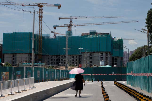 A woman walks near a construction site of apartment buildings in Beijing, China.