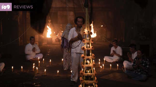 A man dressed all in white conducts a ritual in a space filled with candles in a scene from The Medium.