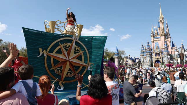 Moana on a parade float, waving at guests at Disney World.