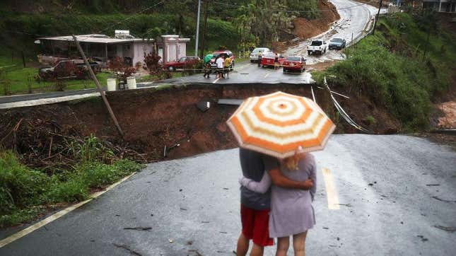 People look on at a section of a road that collapsed and continues to erode days after Hurricane Maria swept through the island on October 7, 2017 in Barranquitas, Puerto Rico.