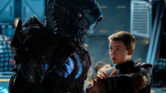 Netflix's Lost in Space robot looks down at a slightly older Will Robinson. 
