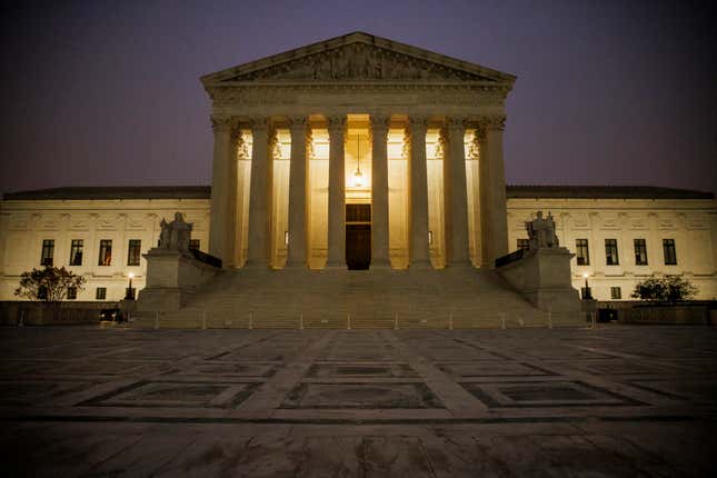 A front-on view of the US Supreme Court in the early morning, set against a dark sky.
