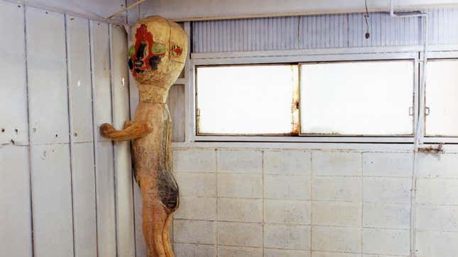 A creepy sculpture in a desolate room.