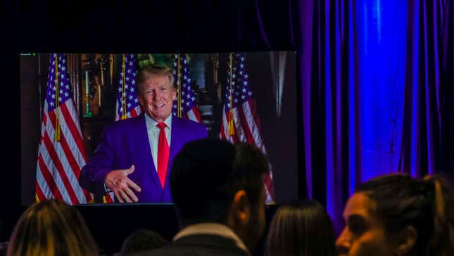 Donald Trump on a television screen in front of a crowd