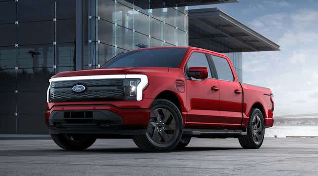 A red 2023 Ford F-150 Lightning is parked in front of a glass building.