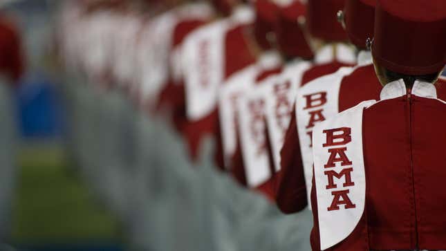 a line of Alabama marching band members lined up on the football field