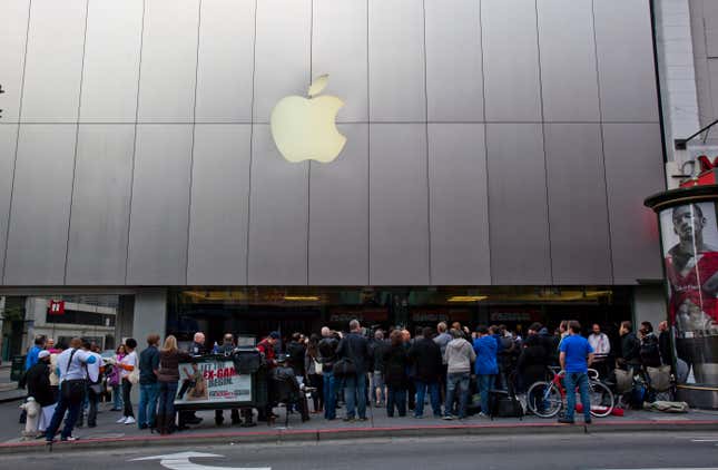 A crowd of people stand outside an Apple storefront.