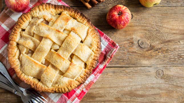 An apple pie with a lattice crust sits on a table.