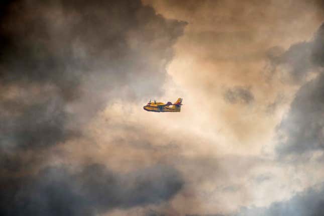 An emergency aircraft flies through the smoke.