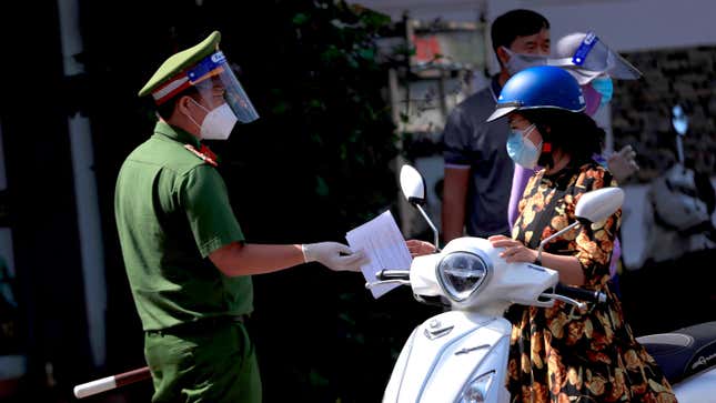 A policeman hands back the travel permit to a commuter after checking at
 a street checkpoint in Vung Tau, Vietnam on Monday, Sept. 6, 2021.