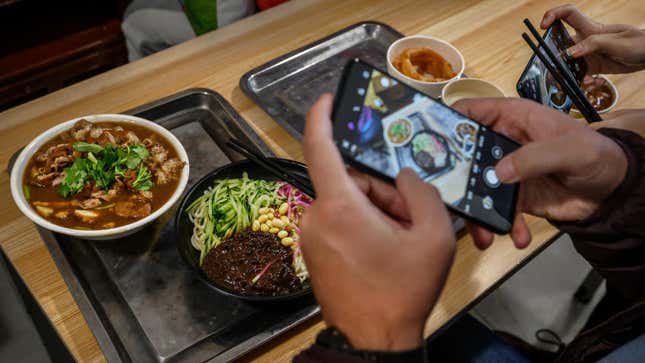 Person taking picture of noodle dish with phone