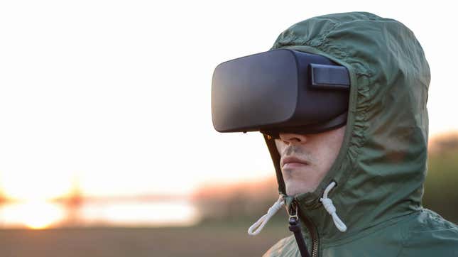 A man in a large green military coat wears a VR headset.