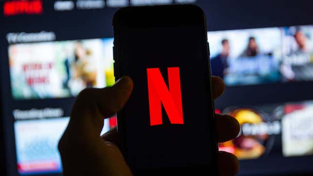 A person holds a phone with the red Netflix logo on its screen. 