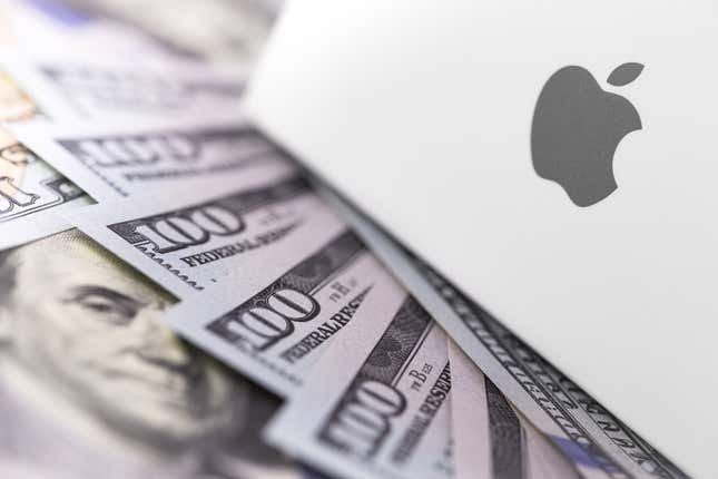 An Apple laptop on a pile of money.