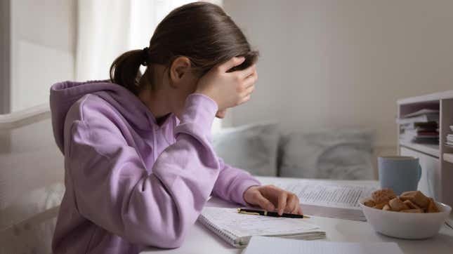 Young girl studying, having trouble focusing, holding head in hand