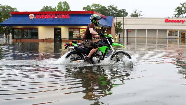 A motorbike rider drives through floodwaters 