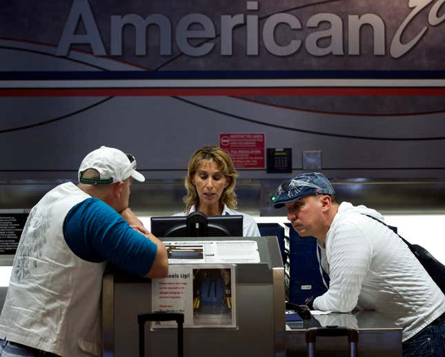 Two unidentified American Airlines passengers talk to a customer service representative, center in Miami.