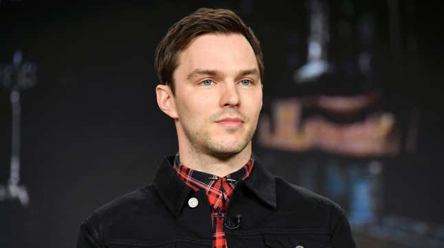 Actor Nicholas Hoult speaks to press wearing a red plaid shirt and black jacket.