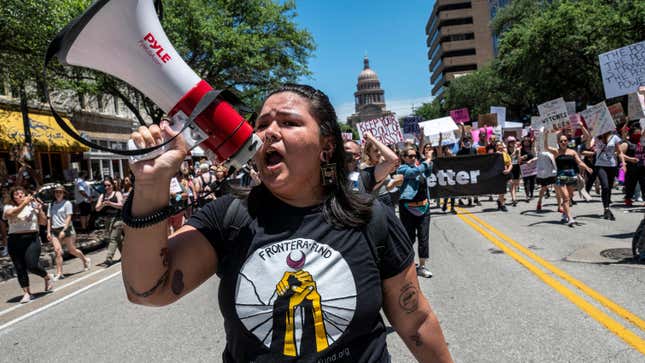 Protesters hold up signs as they march down Congress Ave at a protest outside the Texas state capitol on May 29, 2021 in Austin, Texas.