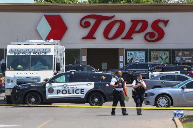 Police walk outside the Tops grocery store on May 15, 2022, in Buffalo, N.Y. A white 18-year-old wearing military gear and livestreaming with a helmet camera opened fire with a rifle at the supermarket, killing and wounding people in what authorities described as “racially motivated violent extremism.” 