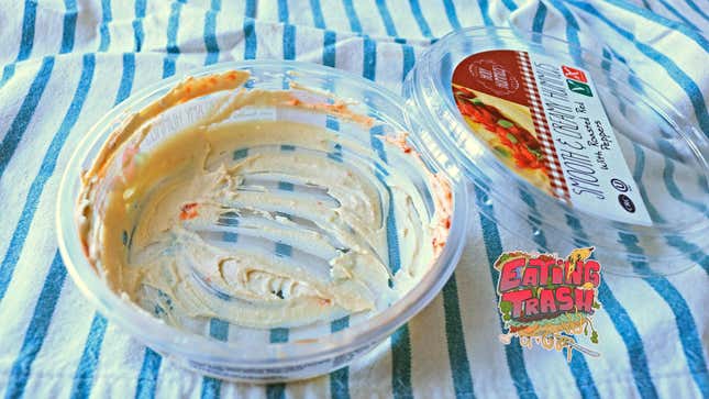 Nearly empty tub of hummus sits on a table cloth.