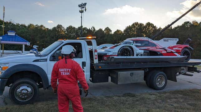 Porsche race car being driven away on a flatbed