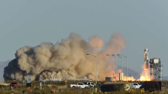 A photo of a blue origin rocket taking off with a big cloud of brown smoke. 