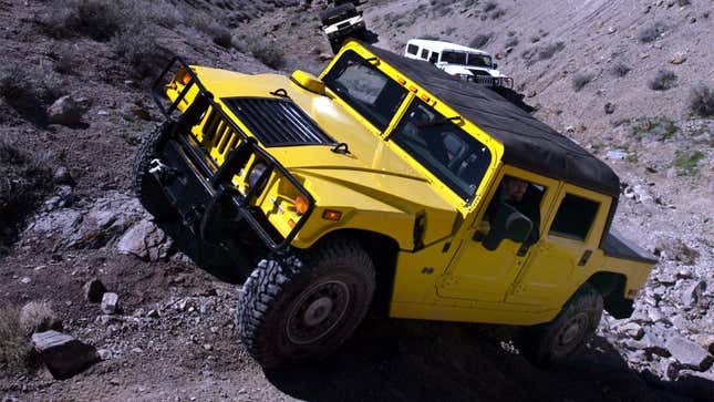 A photo of a yellow Hummer H1 car driving off road.