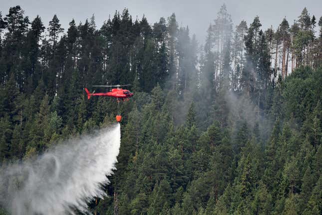 A helicopter drops water at a wildfire next to the village Grotingen in Bracke municipality in central Sweden on July 22, 2018.