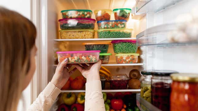 Woman placing leftovers into fridge full of food