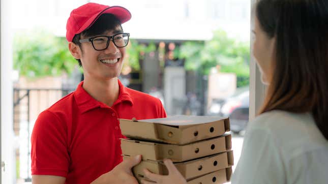 delivery driver handing pizza boxes to woman