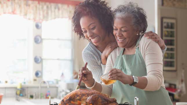 Two women embracing and preparing Thanksgiving turkey