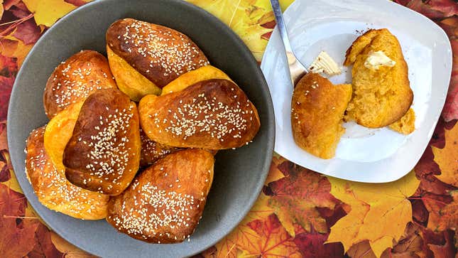 Bowl of Sweet Potato Parker House Rolls and one sliced open on a plate with butter
