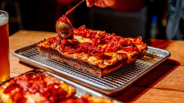 sauce being ladled onto detroit pizza