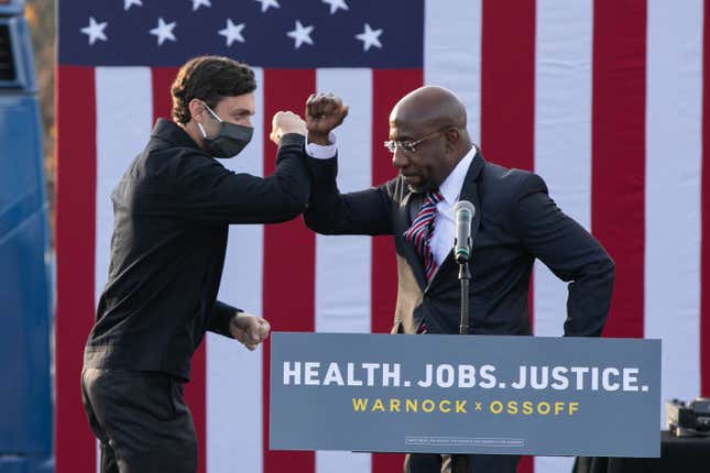 Georgia Democratic Senate candidates Raphael Warnock (R) and Jon Ossoff (L) bump elbows during a "It's Time to Vote" drive-in rally on December 28, 2020 in Stonecrest, Georgia. 