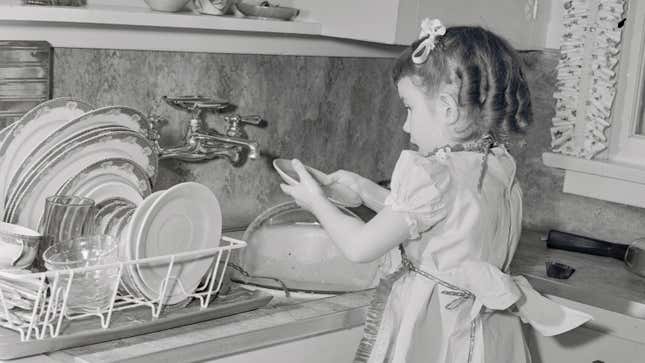 A girl washing dishes at the sink in a vintage black and white photo