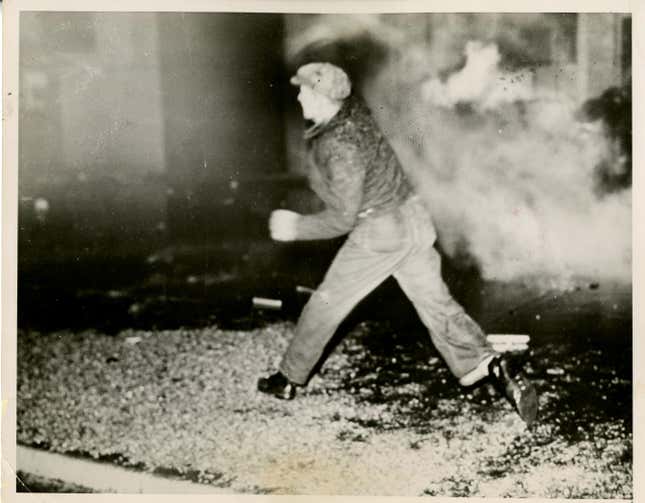 Worker ignores tear gas, throws rocks at police as he enters Fisher #1 to relieve sit-down strikers on Jan. 2, 1937